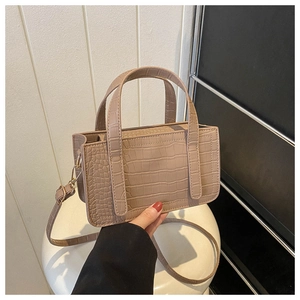 Close-up of khaki faux crocodile texture on stylish small square handbag for women