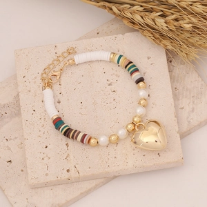 Detail of bohemian bracelet with clay beads, pearls and golden heart pendant
