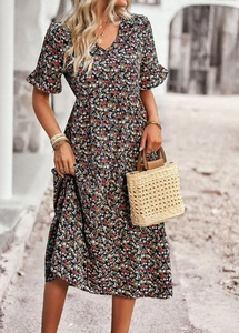 Full-body shot of a floral print V-neck maxi dress with a woven straw handbag
