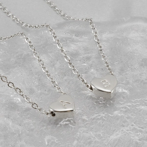 Colliers pendentifs coeur en acier avec lettres gravées A et B sur fond de glace