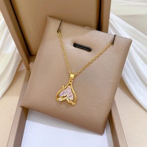 Close-up of golden fishtail pendant with pink crystal in an elegant jewelry box