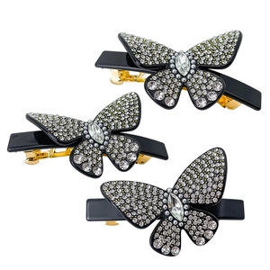 Dettaglio di tre fermagli per capelli a farfalla con strass lucidi e clip a molla dorata