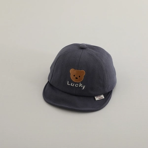 Close-up of baby baseball cap featuring brown bear embroidery and Lucky lettering details