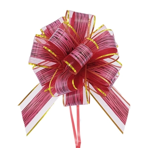 Detailed close-up of a large red textured Christmas pull bow with gold edge and trailing ribbons