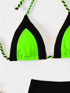 Detailed flat lay of a contrast neon green and black bikini with twisted strap detail