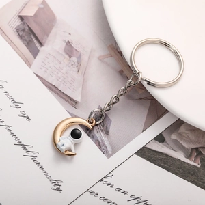 Creative keychain featuring a golden moon and a white astronaut on a metal chain