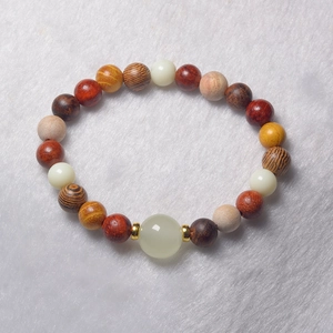 Detail of wooden beads bracelet with metallic spacers on white faux fur background
