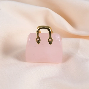 Close-up of pink crystal mini handbag pendant with a gold handle on beige fabric