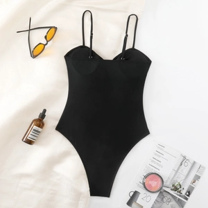 Flat lay of a black V-neck one-piece swimsuit with adjustable straps and vacation props