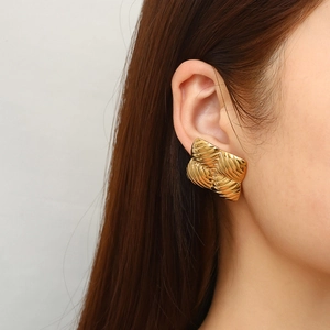 Close-up of gold square earring with vortex texture worn by a model for a luxury look