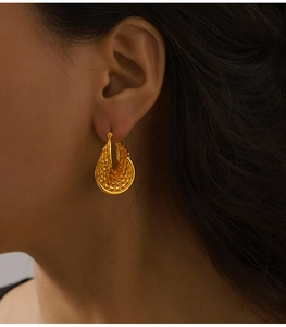 Detail of vintage gold-plated drop earrings with textured weave on a fashion model