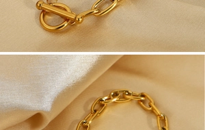 Macro detail of golden paperclip chain link and OT toggle clasp on champagne silk satin