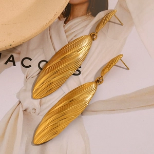 Detail of vintage gold-tone striped long shell pendant earrings on a magazine backdrop