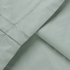 Gros plan détaillé du pantalon cargo vert sauge montrant les coutures précises et le tissu