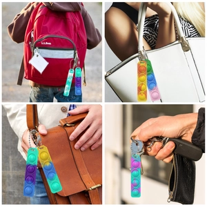 Rainbow silicone pop it keychain fidget toy shown as accessory on backpacks and bags
