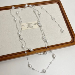 Close-up of long multilayer grey pearl necklace with baroque pearls on white fabric