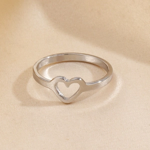 Bague minimaliste en acier inoxydable argenté avec motif cœur évidé sur tissu beige