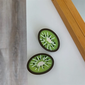 Detail of small acetate hair clips featuring realistic green kiwi fruit slice designs