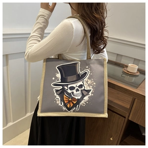 Detail of grey canvas tote featuring a skeleton with top hat and jute woven handles