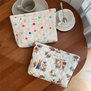 Close-up of quilted cotton storage pouches with cute bunny prints and colorful dots on a table