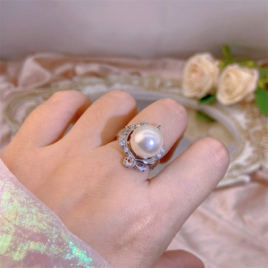 Macro detail of elegant large pearl ring with sparkling zircon-set silver wavy bands
