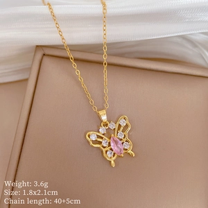Detail view of gold butterfly pendant with pink oval stone and crystal pavé on a stand