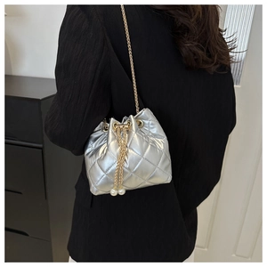 Detail of silver quilted bucket bag with gold chain and pearl drawstring charms