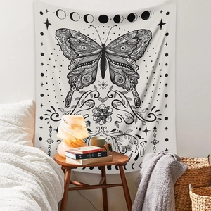 Detail view of black and white bohemian tapestry with butterfly and moon phases on bedroom wall