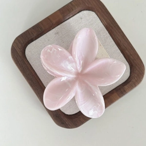 Pink plumeria hair claw clip with a marbled resin finish for elegant hairstyles