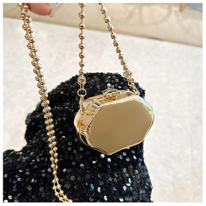 Close-up of a mini gold metal bag with beaded chain on a black sequined background