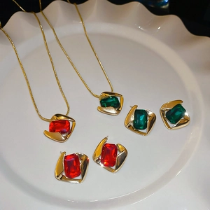 Detail of red and green geometric gem pendant necklaces and stud earrings on a white plate