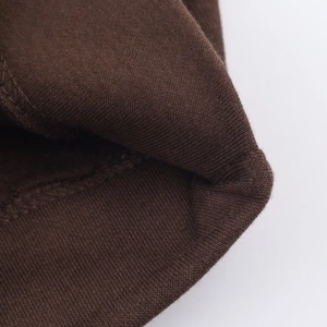 Gros plan détaillé du tissu en velours marron foncé de la veste avec couture d'ourlet