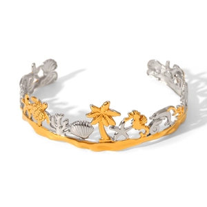 Macro detail of ocean-themed open bangle with golden palm tree and sea creature motifs