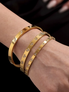 Close-up of three gold stainless steel bracelets with zircon stones on a model's wrist