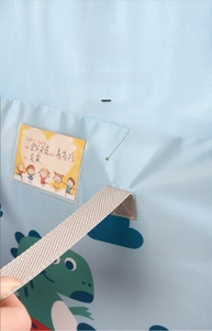 Detail of thickened reinforced handles and name tag slot on blue dinosaur quilt storage bag