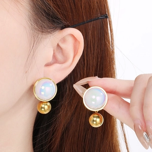 Model wearing gold hoop earring with a pearlescent white bead and gold drop detail