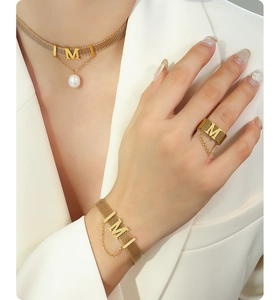 Detailed view of golden mesh jewelry set with letter M and elegant pearl pendant