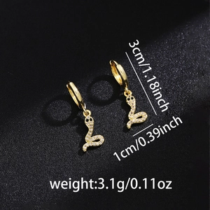 Macro detail of a snake-shaped drop earring in gold finish with white zircon inlay
