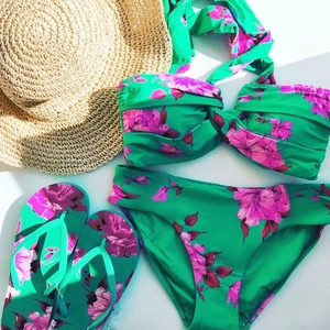 Flat lay of floral bikini set with matching flip flops and straw hat for beach vacation