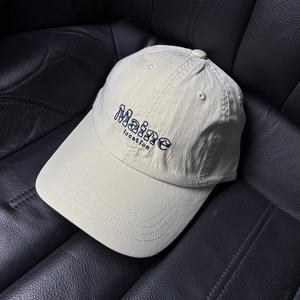 Détail de la broderie Maine sur une casquette de baseball en coton crème avec œillets d'aération