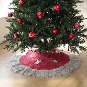 Red Christmas tree skirt with grey plush trim and white snowflakes in a home setting