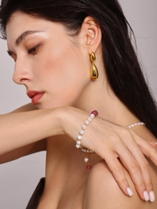 Boucles d'oreilles goutte dorées et bracelet de perles avec perles rouges sur un mannequin