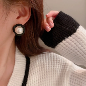 Gros plan d'une boucle d'oreille ronde noire avec une grande perle d'imitation blanche