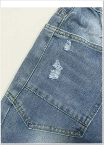 Detailopname van vintage blauwe jeans met versleten zakken en gele contraststiksels erop