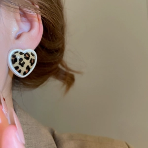 Close-up of heart-shaped leopard print earring with cream white frame on female model