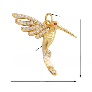 Detailed view of gold hummingbird pendant with white zircon inlays and ruby eye