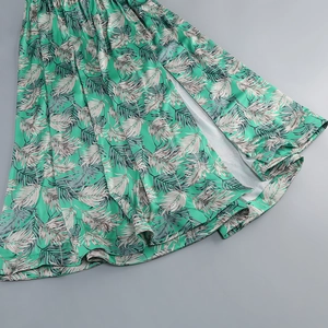 Detail of tropical palm leaf print on green and white maxi dress with side slit