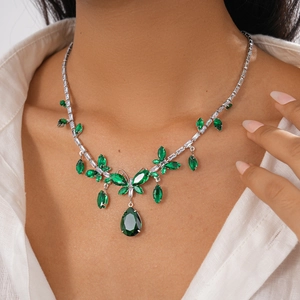 Detail of vintage necklace with green drop pendant and marquise gems on neck