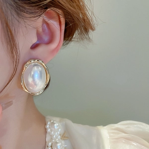 Gros plan de boucles d'oreilles perles ovales avec bordure dorée texturée pour femmes