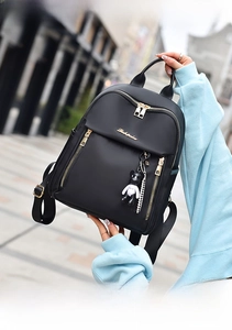 Detail of black waterproof nylon backpack featuring gold zippers and a bear keychain